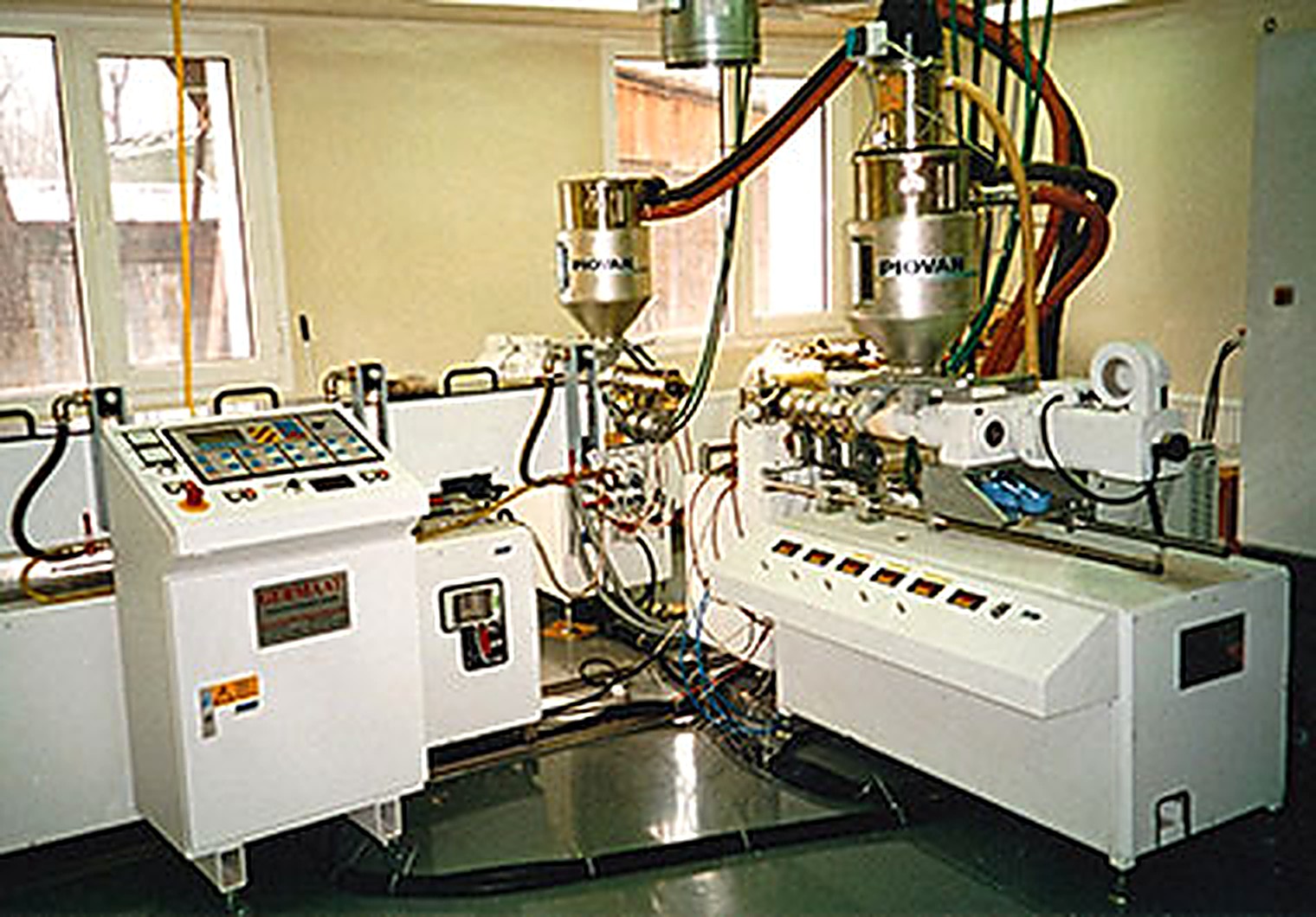 Doppelschneckenextruder mit zwei Dosiertrichtern und Schaltschrank in der Fertigung.