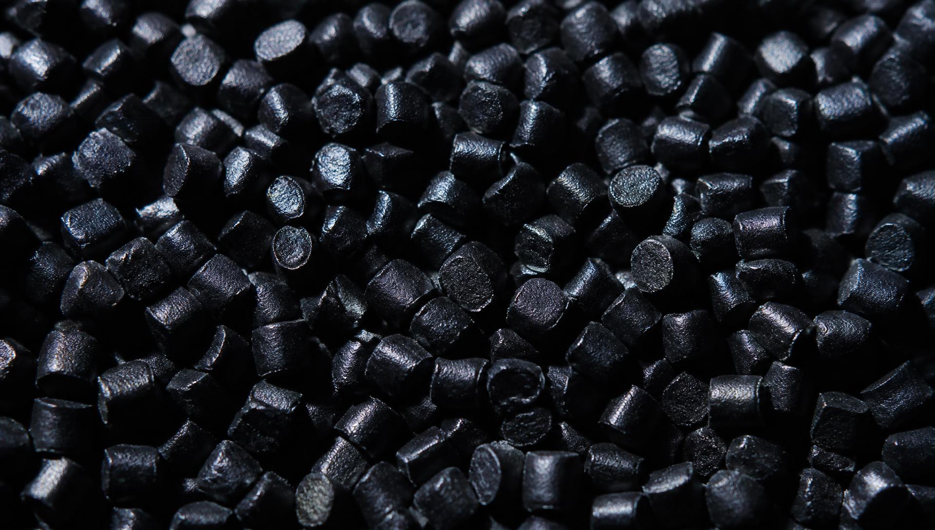 Makroaufnahme von tiefschwarzem, mattem Nano-Compound-Granulat mit feinem metallischem Schimmer in den Glanzlichtern.