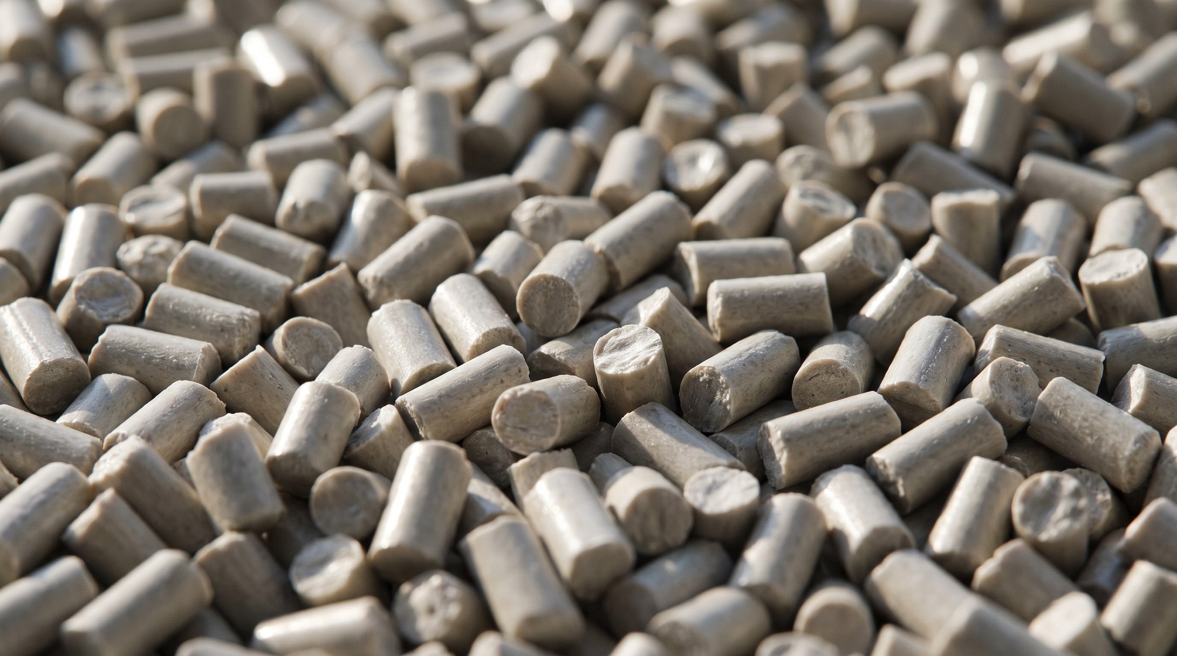 Makroaufnahme von naturfarbenem, grau-beigem Polypropylen-Zylindergranulat.